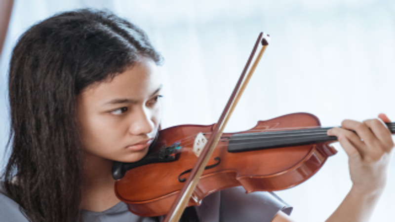 A girl with straight dark hair plays a violin.